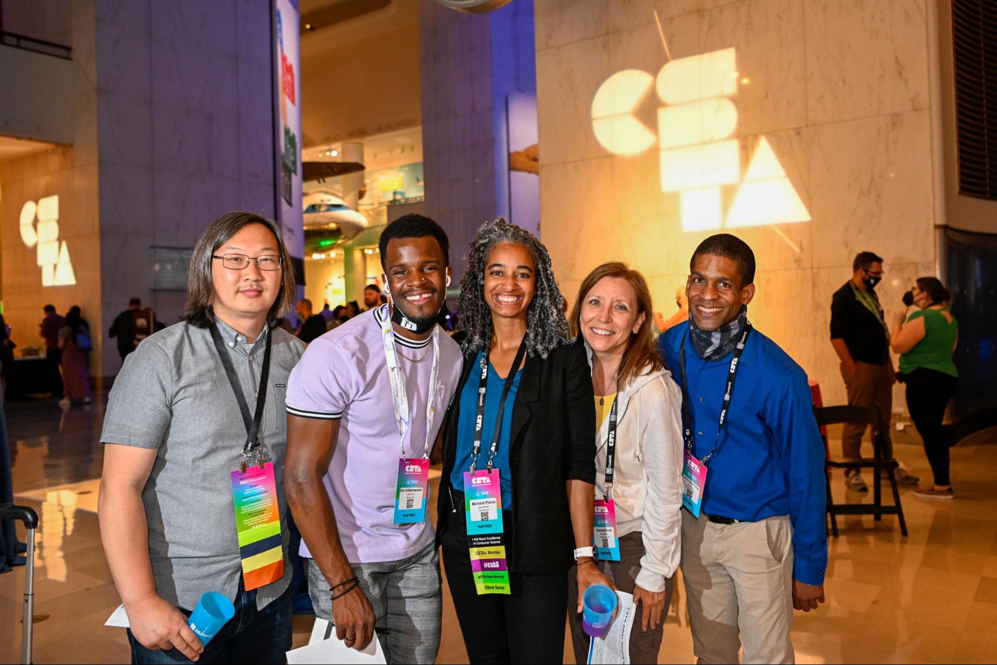 A group of five CS advocates pose for a group photo in front of CSTA logos. 