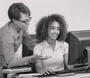 Photo of a black woman teaching a young black student computer science