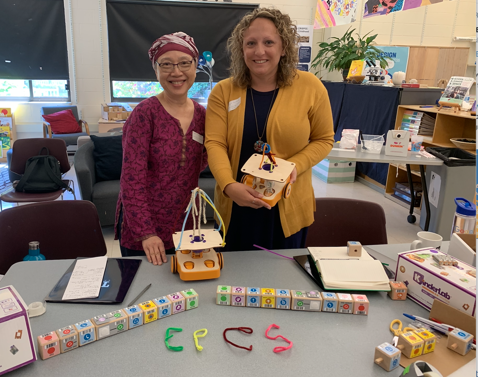 Two teachers posing with KIBO robots in a kindergarten class. This image is from a linked article on choices of conduct and fostering creativity, curiosity and generosity through robotics